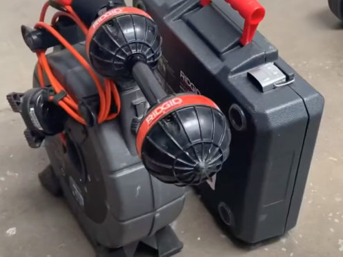 A Ridgid inspection camera system with cables and two camera heads is placed on the floor next to a black Ridgid carrying case with a red handle. | High 5 Plumbing, Heating & Cooling