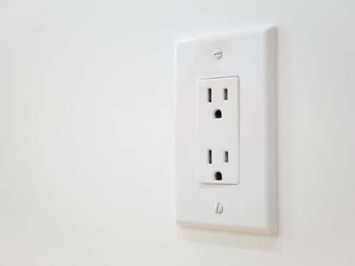 A white electrical outlet with two sockets is mounted on a white wall. The outlet cover, secured with two visible screws, may need electrical outlet troubleshooting if the power outlet is not working but the breaker not tripped. | High 5 Plumbing, Heating & Cooling