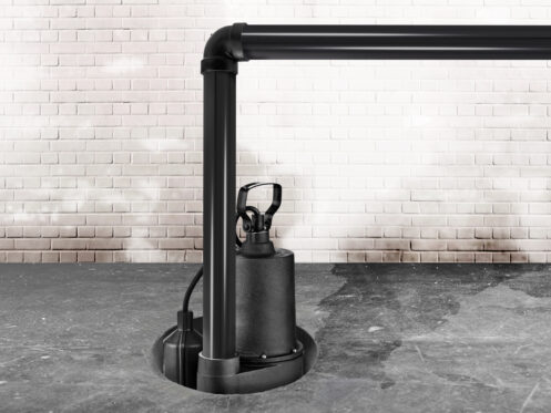 A black sump pump with high sump pump capacity is installed in a circular pit on a concrete floor, connected to black PVC pipes, with a white brick wall in the background. | High 5 Plumbing, Heating & Cooling
